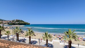 A beach with palm trees, umbrellas, and people. - Greco BeB (Agropoli)