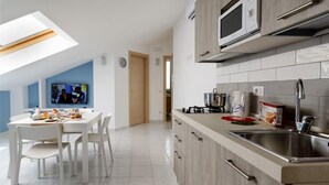 A modern kitchen with a dining area, a TV, and a skylight. - Greco BeB (Agropoli)