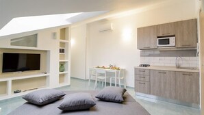 A modern, compact living space with a bed, a TV, a dining area, and a kitchenette. - Greco BeB (Agropoli)