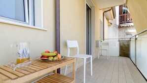 A balcony with a wooden table, a white chair, a fruit bowl, and a glass pitcher. - Greco BeB (Agropoli)