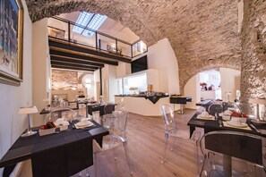 A modern dining area with clear chairs, black tables, and a high ceiling with exposed stone. - Il Palazzo (Assisi)