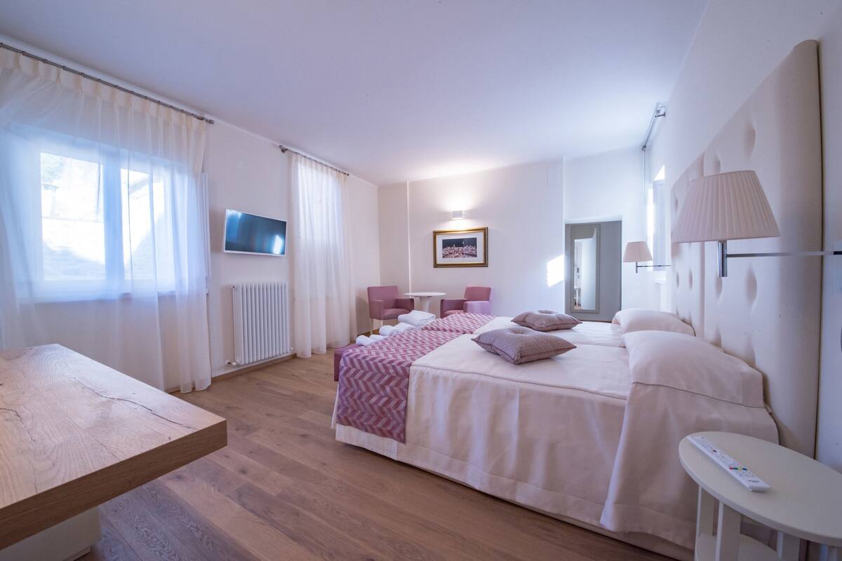 Habitación de hotel con una cama grande, un escritorio, una silla, un televisor y un baño.