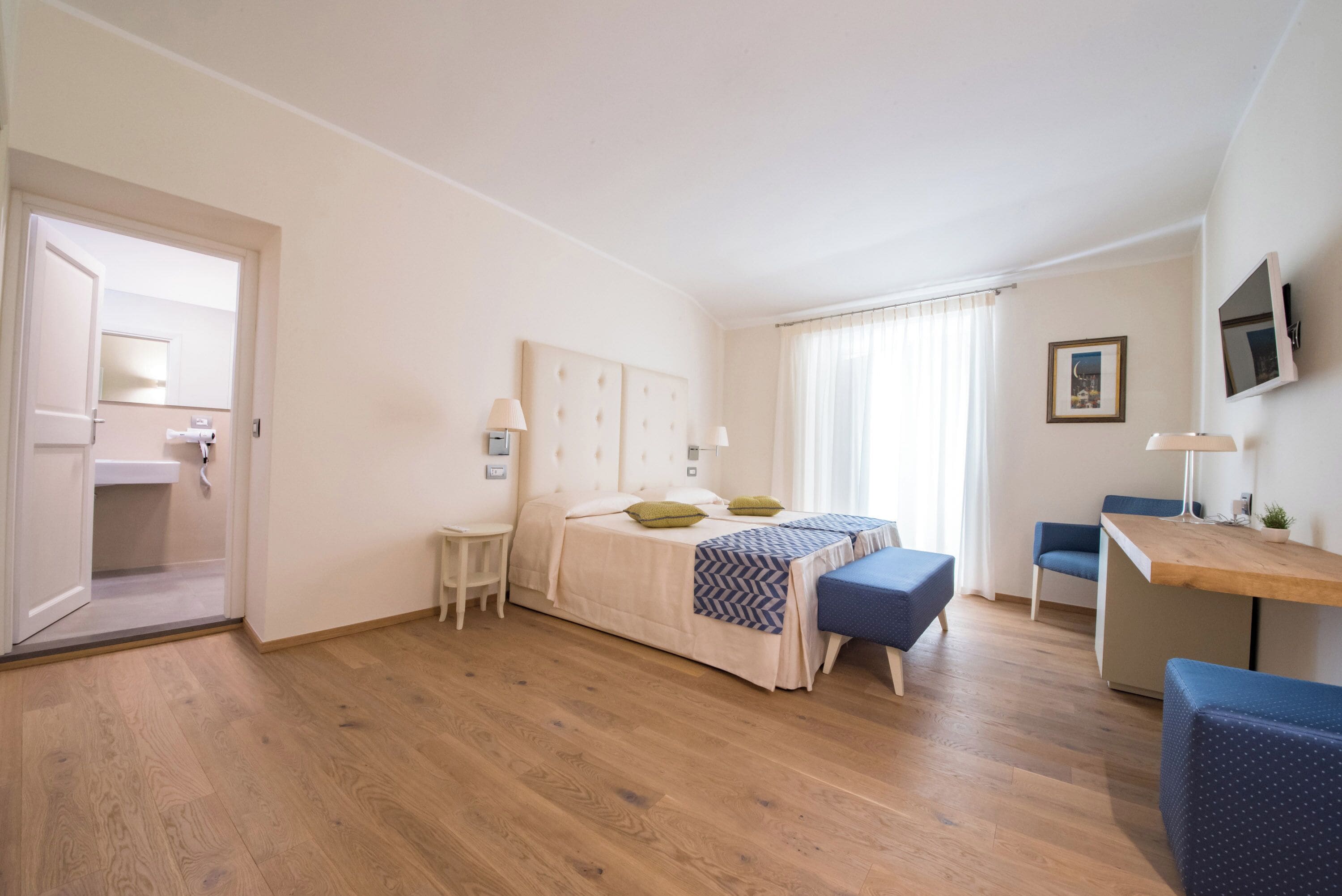 Une chambre à coucher comprenant un lit, des tables de chevet, un bureau et une chaise.