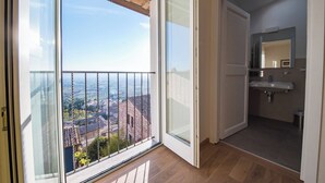 Un balcon offrant une vue dégagée sur le paysage urbain, une salle de bain avec un lavabo et un miroir, et un plancher en bois.