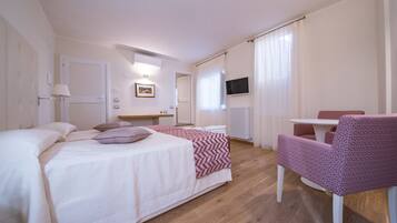 Quarto de hotel com duas camas, uma escrivaninha, uma cadeira, uma televisão e uma janela com cortinas.