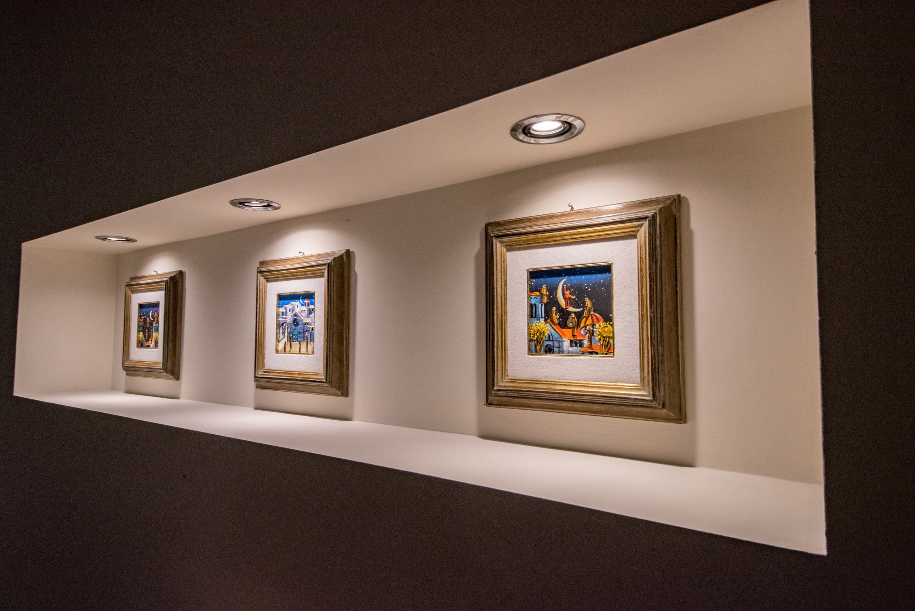 A gallery wall with framed artworks displayed on a white ledge.