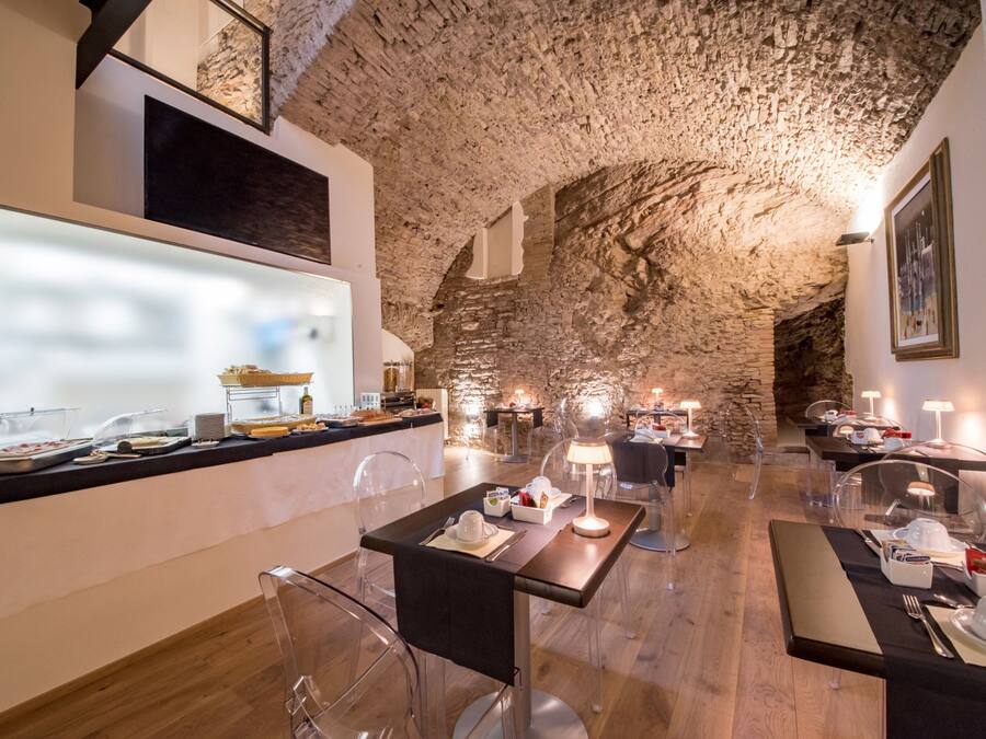 A restaurant with a rustic stone ceiling, clear glass tables, and modern lighting.