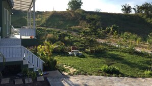 Ein Haus mit überdachter Veranda, einem Rasen und einer hügeligen Landschaft im Hintergrund.
