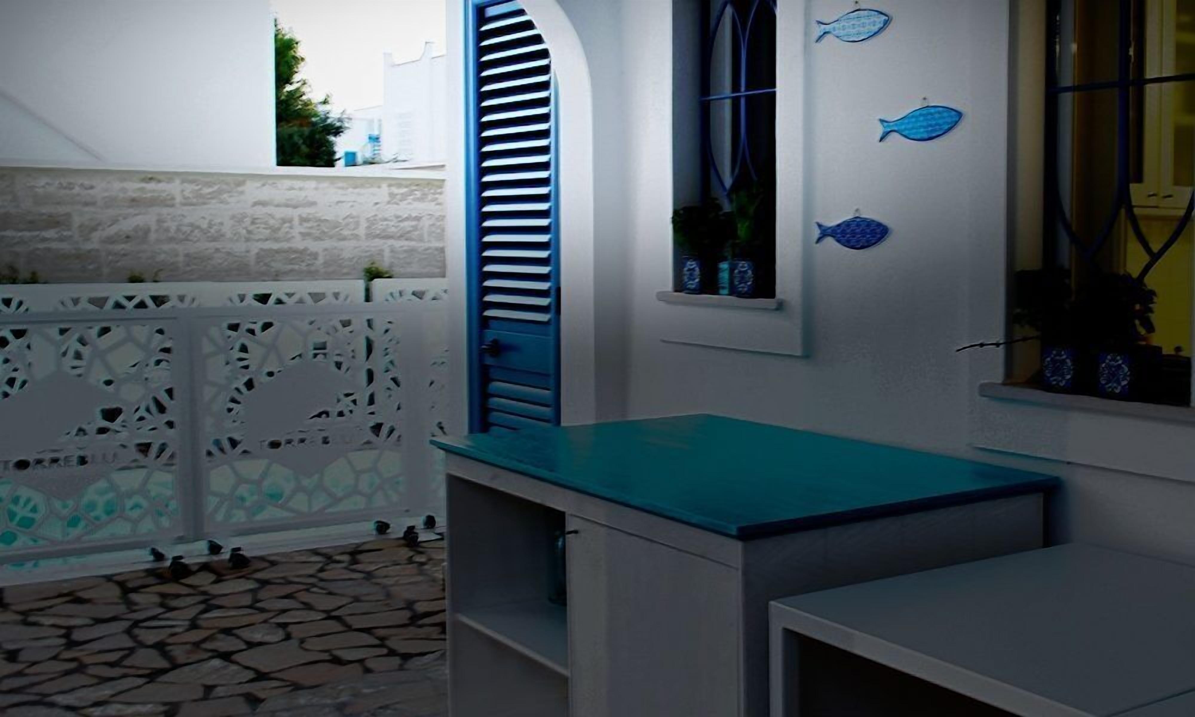 A room with a stone-tiled floor, a white wall with a window, and a blue countertop.