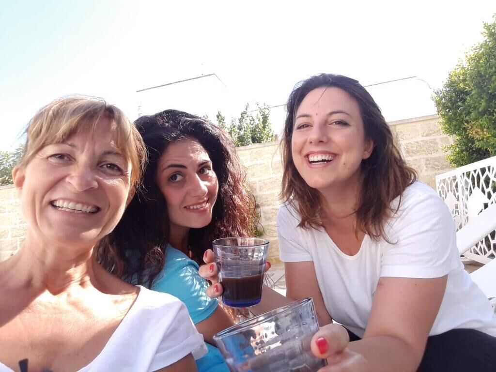 Three people sitting outdoors, holding drinks.