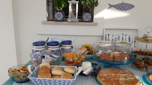 A buffet table with various food items, including bread, pastries, and fruits.