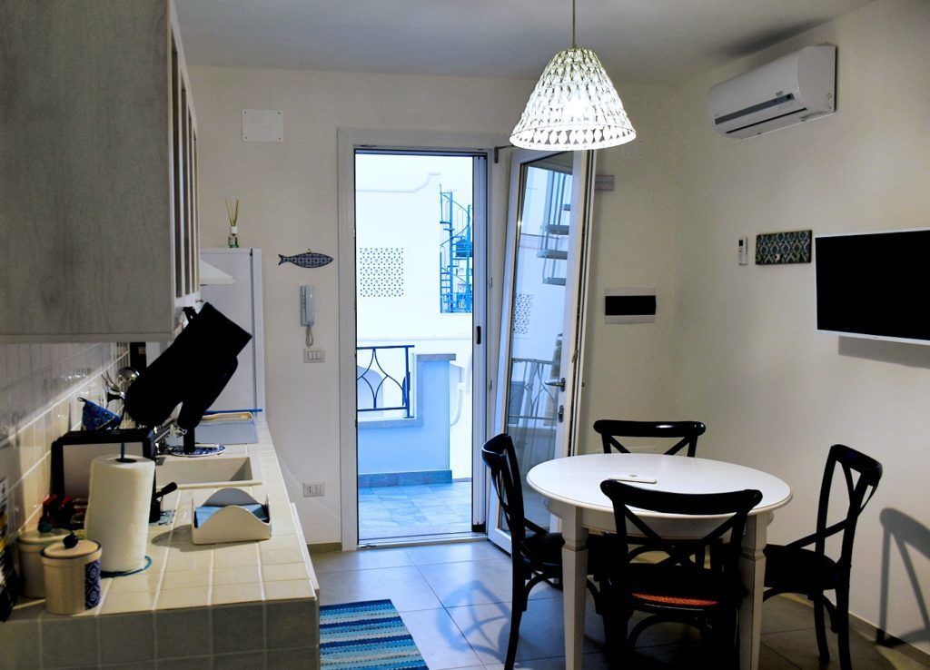A compact kitchen with a dining area, a large window, and an air conditioning unit.