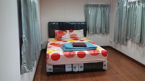 A neatly made bed with a floral-patterned bedspread, a black headboard, and a brown pillow. - Nakhonyok Homestay (Nakhon Nayok)