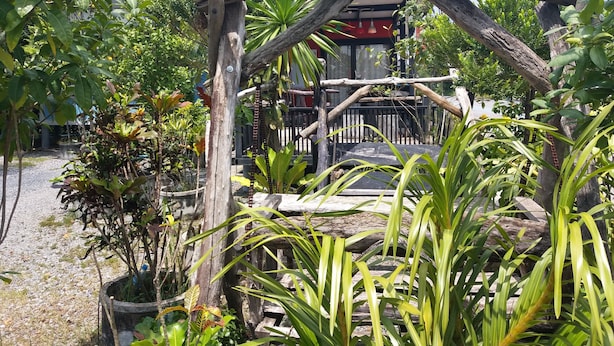 A rustic wooden structure surrounded by lush greenery, possibly a garden or outdoor seating area. - Nakhonyok Homestay (Nakhon Nayok)