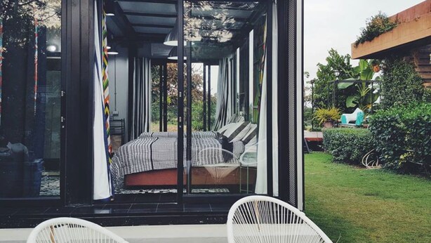 Un espace extérieur moderne et aménagé, avec un lit et deux fauteuils en osier blanc.