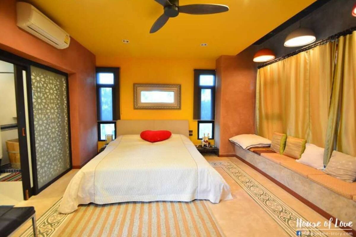 Een hotelkamer met een bed, een plafondventilator, een raam en een gordijn.