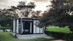 Un bâtiment moderne, de plain-pied, doté d’une porte en verre et d’un petit porche, situé à côté d’une piscine.