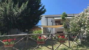A residential building with a balcony, surrounded by greenery and potted plants. - Villa Rosa (Agropoli)