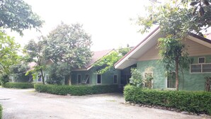 A row of two-story houses with a gravel driveway, surrounded by greenery and trees.