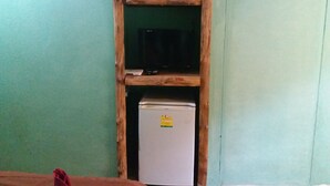 A room with a wooden-framed shelf containing a TV and a white refrigerator.