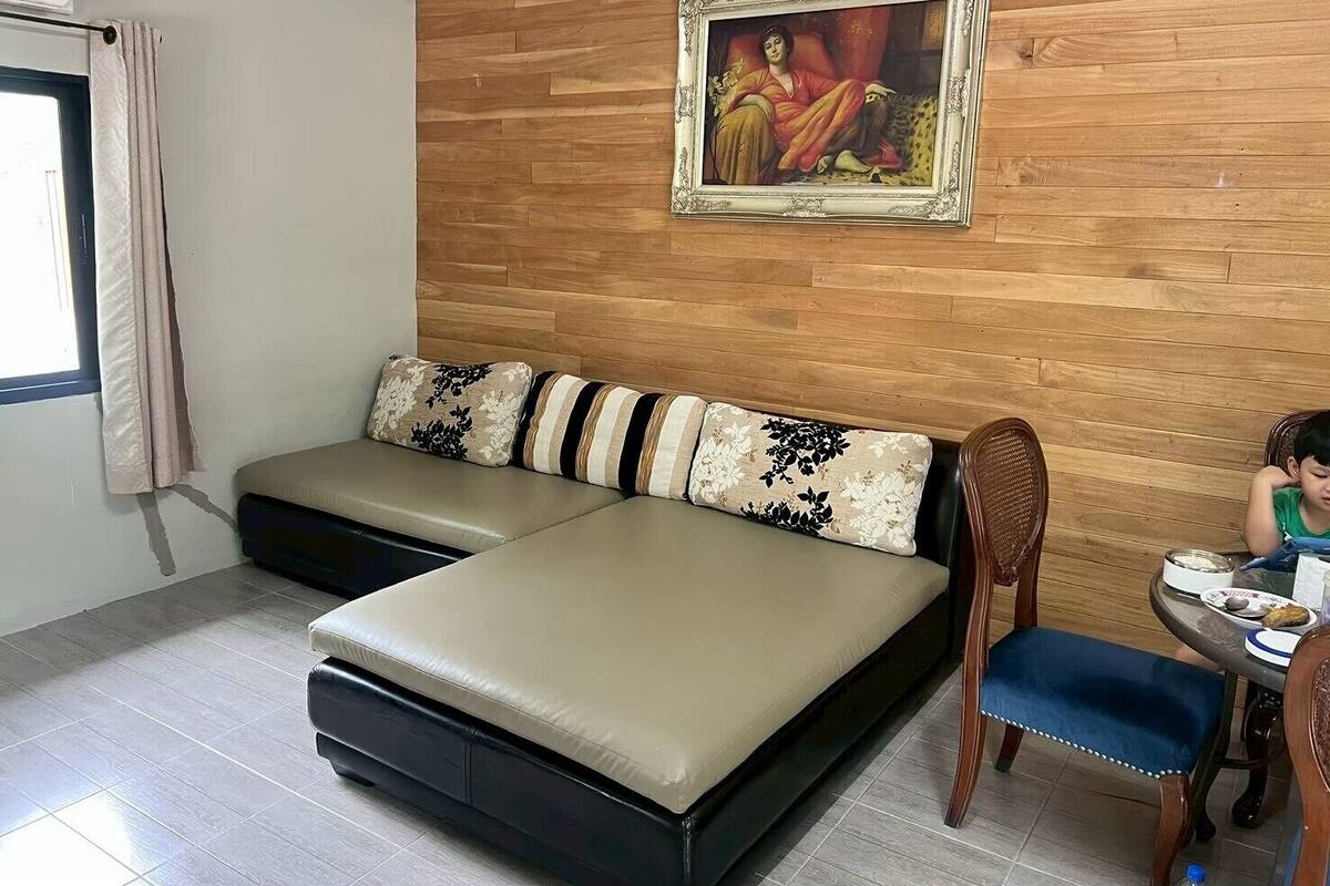 A room with a sofa bed, a dining table with chairs, and a painting on the wall.