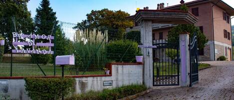 A gated entrance with a sign reading "BE AMOR DI LAVANDA" and a building with a stone facade and a balcony.