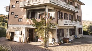 Un bâtiment à deux étages, doté d’un balcon au deuxième étage, d’une façade en briques et d’une cour pavée.