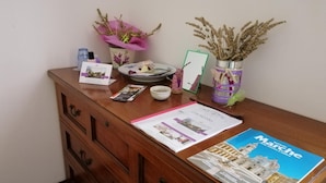 Un bureau en bois, orné de brochures, d’un tableau encadré, d’un petit bol et de plantes décoratives.