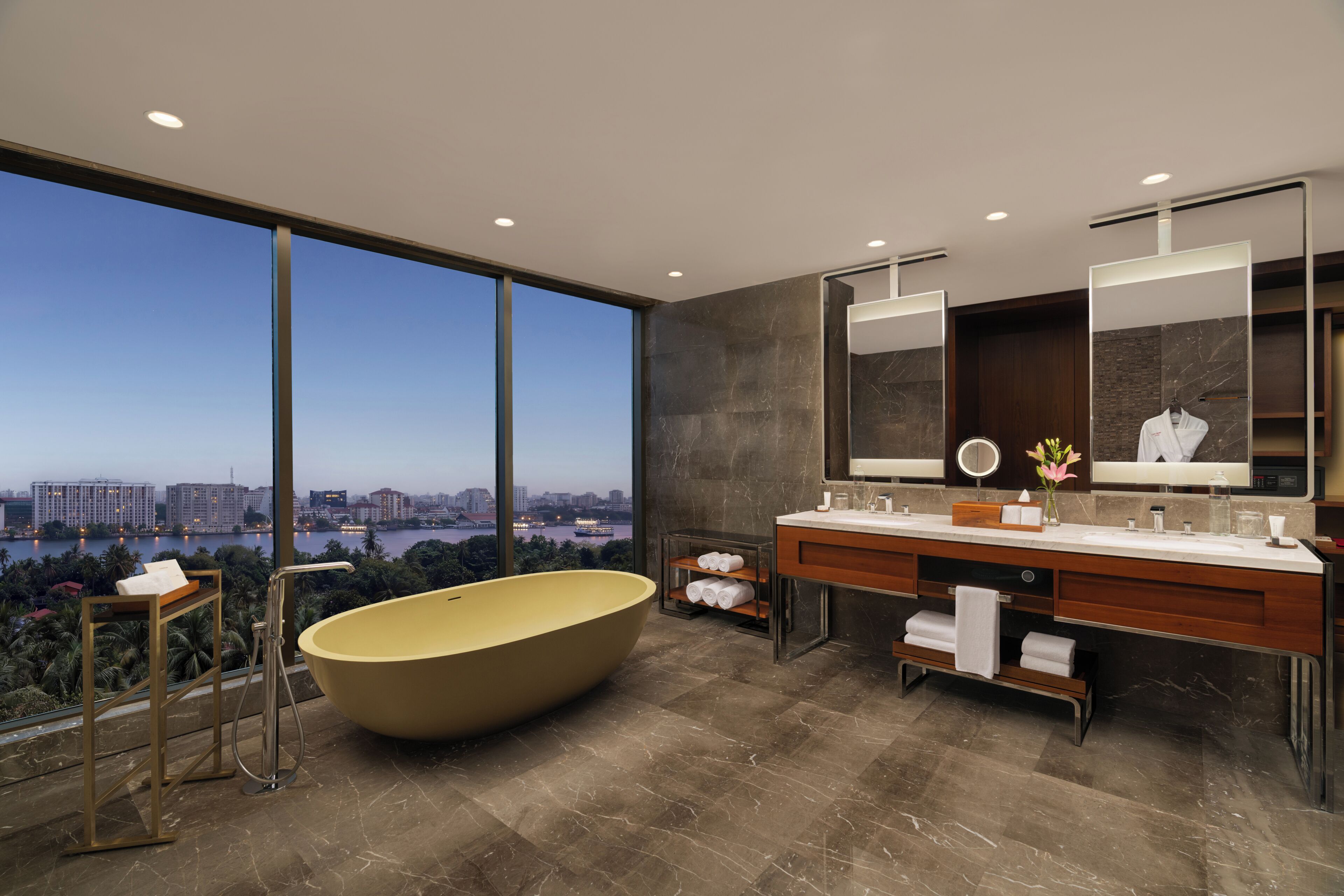 A modern bathroom with a large bathtub, a vanity with a mirror, and a view of a cityscape.