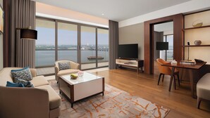 Ein modernes Wohnzimmer mit Sofa, Couchtisch, Fernseher und Blick auf das Wasser.