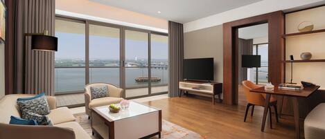 A modern living room with a sofa, coffee table, TV, and a view of the water.