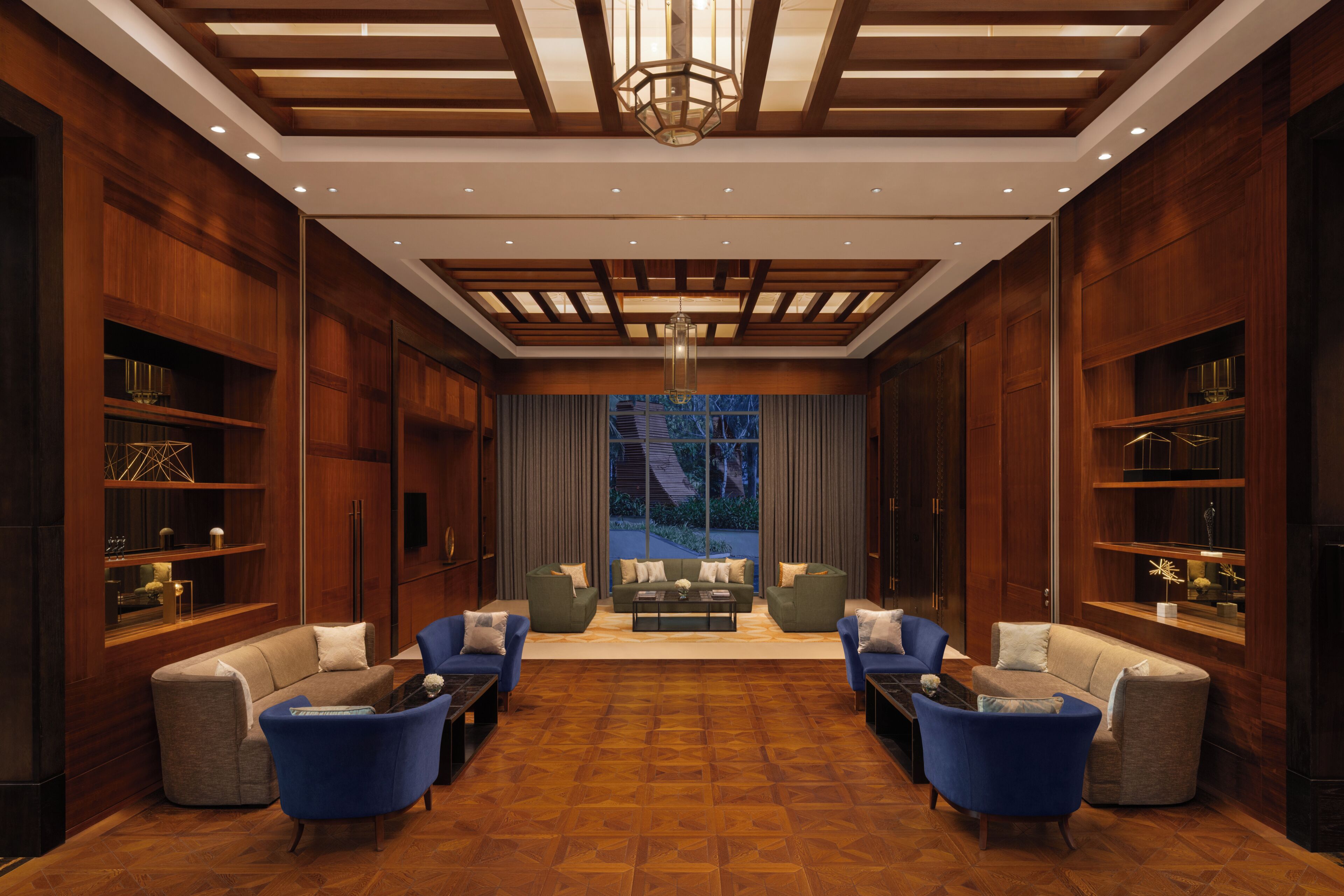 A spacious lobby with a central seating area, wooden paneling, and a large window providing a view.