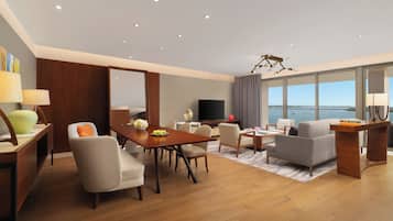 A modern living room with a dining area, a flat-screen TV, and a large window with a view.
