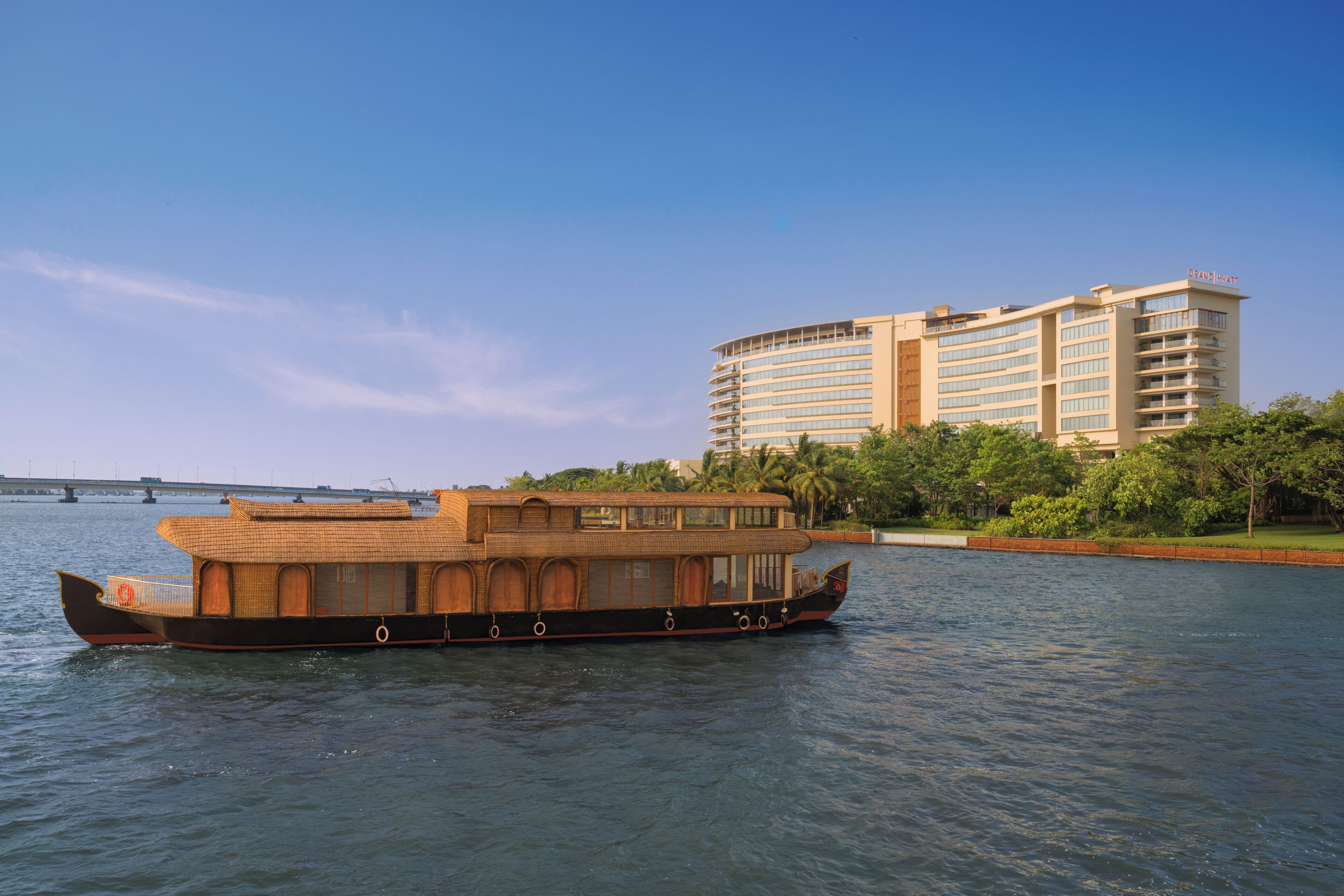 Un barco de recreo fluvial con cubierta cerrada y un edificio al fondo.