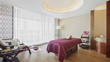Relax in a serene space with a neatly made bed, wooden desk, and a small table with fresh fruit.