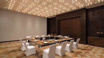 A conference room with a long table, white chairs, and a patterned carpet.