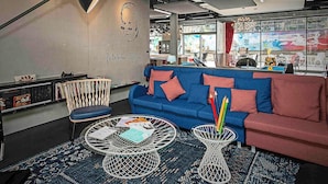 Um interior moderno com um sofá azul, uma mesa de centro de metal, uma parede com um retrato e vista através de grandes janelas.