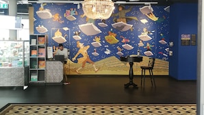 Quarto com piso estampado, um lustre e um mural com diversos personagens.