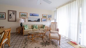 A living room with a sofa, armchair, coffee table, and a ceiling fan. - Turtle Bay Sea Shells. (Kahuku)