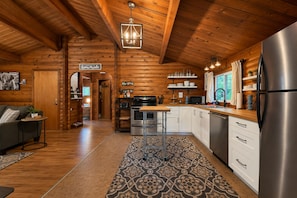 Cucina in stile baita con isola centrale, elettrodomestici in acciaio inossidabile e lampadario a sospensione.