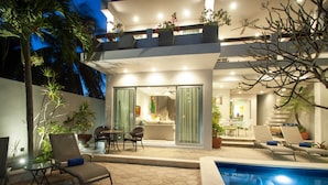 Une maison moderne dotée d’une piscine, d’un espace salon extérieur et d’un coin repas.