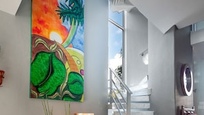 Un intérieur moderne avec un sol en marbre, un escalier et un grand tableau abstrait accroché au mur.