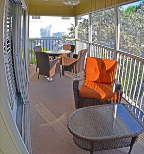 Relax in this serene outdoor space with a view of lush surroundings, featuring a wicker table and chairs.