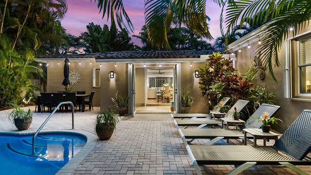 A pool area with lounge chairs and a dining area, surrounded by tropical plants. - Private Tropical Escape Near Fort Lauderdale Beaches & Dining! (Fort Lauderdale)