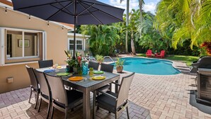 An outdoor patio with a pool, wicker furniture, and a grill. - Private Tropical Escape Near Fort Lauderdale Beaches & Dining! (Fort Lauderdale)