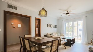 A dining area with a wooden table and chairs, a ceiling fan, and a large window with curtains. - Estrella Del Mar H6_200Mbps_BBQ_Pool_Walk to Beach (Bavaro-Punta Cana)