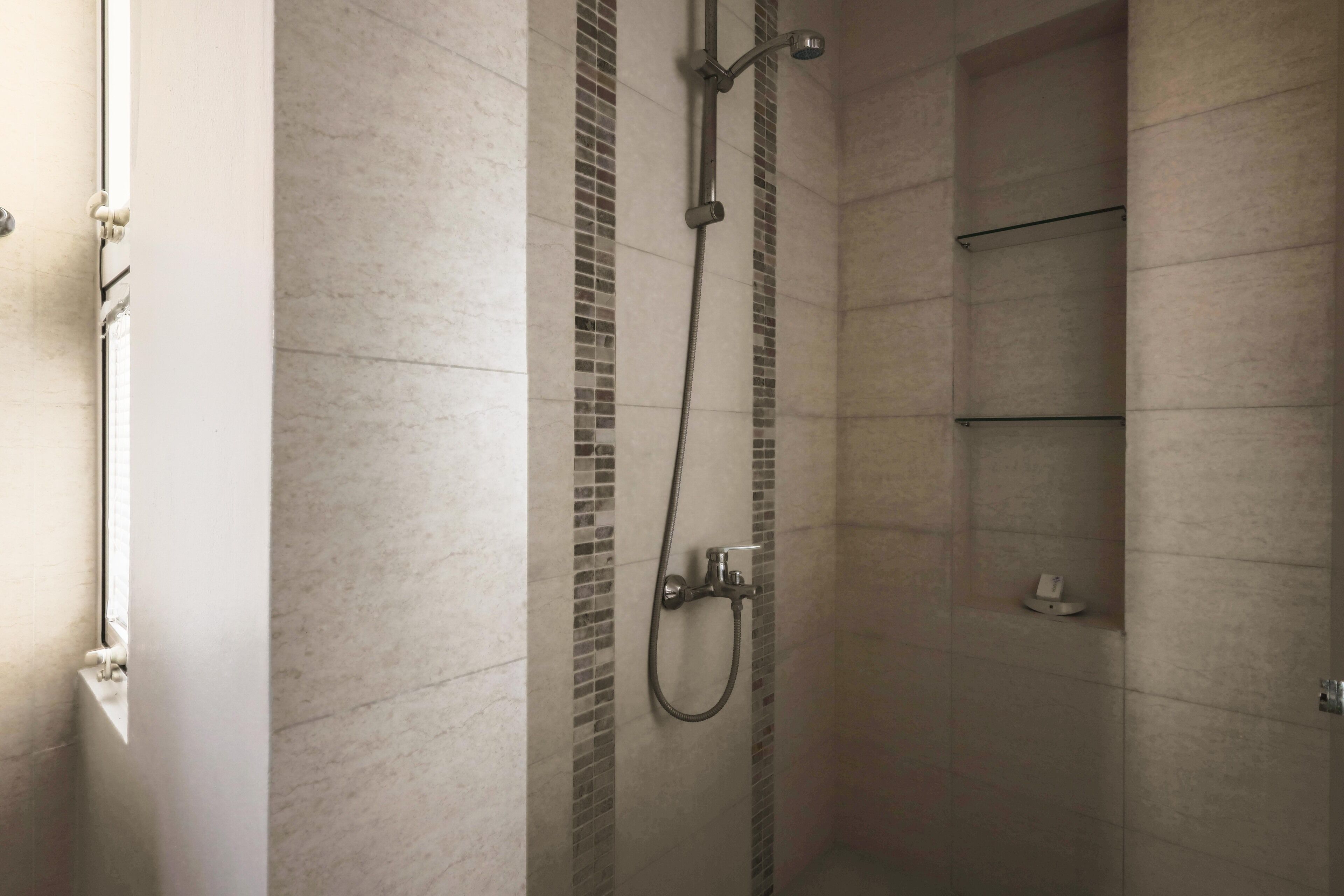 A shower with a handheld showerhead and a wall-mounted faucet.