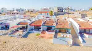 Un hôtel situé sur la côte, composé de plusieurs bâtiments, chacun doté d’un toit recouvert de tuiles et d’espaces extérieurs aménagés pour se détendre.