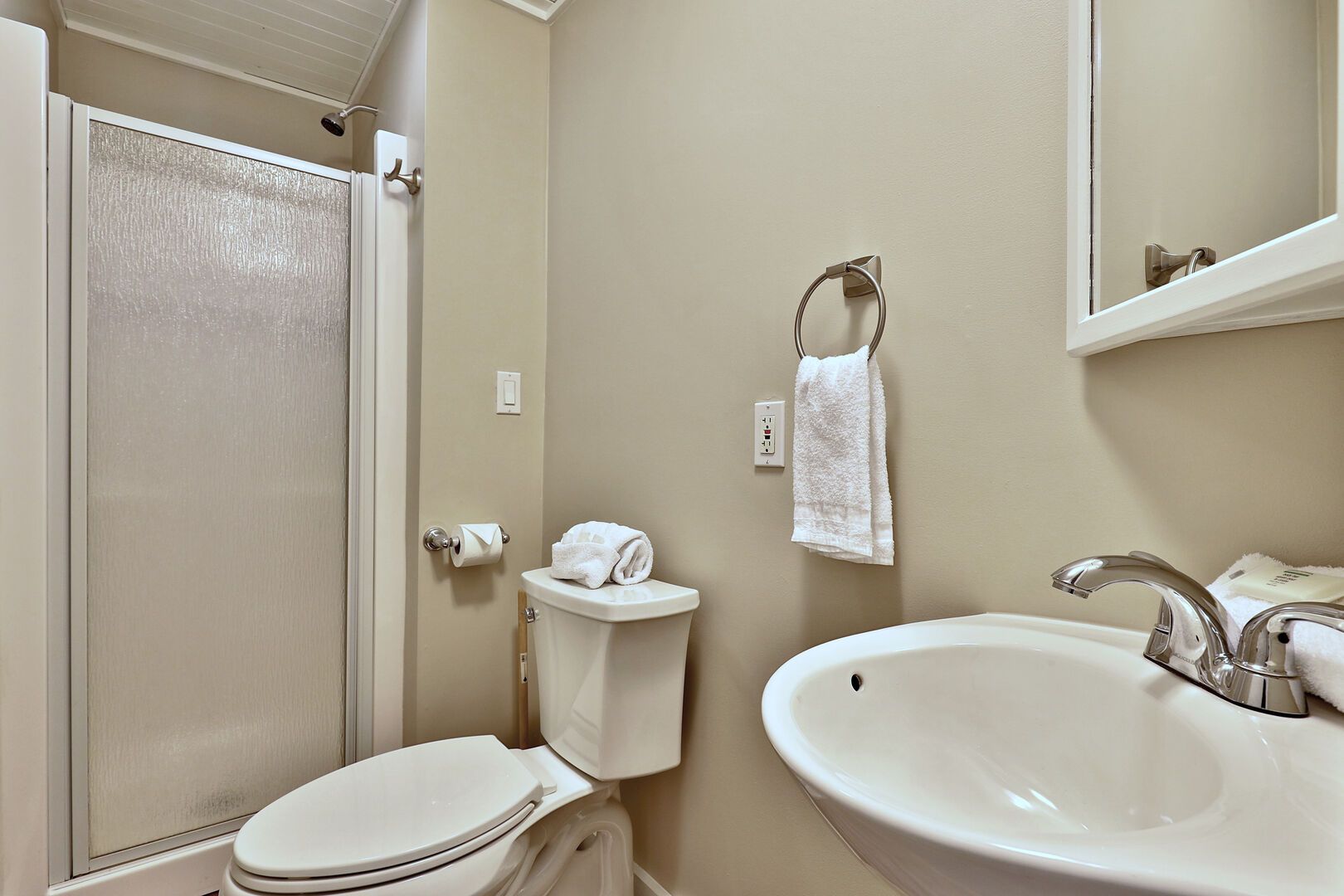 Un baño con inodoro, lavamanos y perchero para toallas.