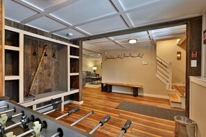 A modern interior with a wooden floor, a bench, a wall-mounted light fixture, and a staircase.